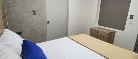 Un dormitorio con cama, armario, mesita de noche y aire acondicionado.