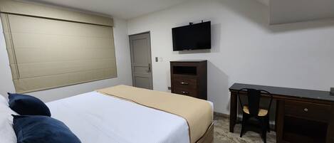 Une chambre à coucher comprenant un lit, un bureau, une chaise, une télévision et une armoire.
