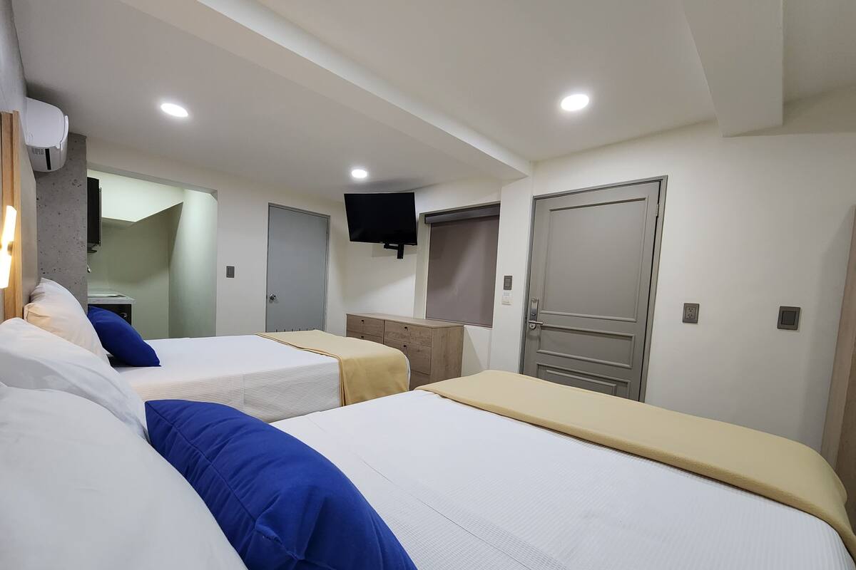 A hotel room with two beds, a TV mounted on the wall, and a door with a window.