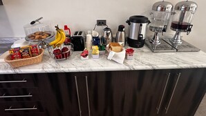 A kitchen counter with various items including a coffee maker, toaster, and food containers. - Hotel Roque (Torreón)