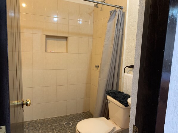 Un baño con ducha, inodoro y perchero para toallas.