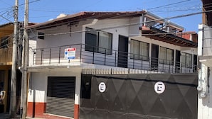 Un immeuble de deux étages doté d’un balcon, d’une porte de garage fermée et d’une enseigne indiquant que des logements sont disponibles à la location.