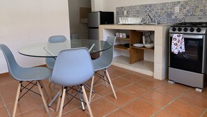 Une cuisine compacte avec une table à manger en verre, deux chaises, une cuisinière et un four à micro-ondes.
