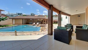 An outdoor swimming pool area with lounge chairs and a covered patio. - 2 suítes ideal p/ amigos e casais (Aquiraz)