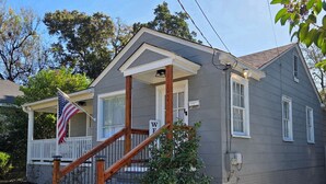 Une maison à deux étages avec un porche à l’avant, un drapeau et une pancarte indiquant « Pas de démarcheurs ».