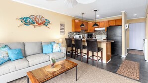 A modern kitchen with a central island, bar stools, and a ceiling fan.