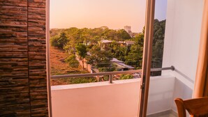 Un balcón con vistas a una zona residencial, una silla de madera y un muro de piedra.