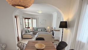 A dining area with a wooden table, wicker chairs, and a woven light fixture. - Villa MAESO, sea views, air conditioning, pool, 8 pax (Son Bou)