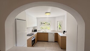 A compact kitchen with white cabinets, a built-in oven, a microwave, and a dishwasher.