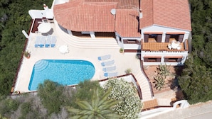 A large house with a swimming pool, multiple lounge chairs, and a covered patio area. - Villa MAESO, sea views, air conditioning, pool, 8 pax (Son Bou)