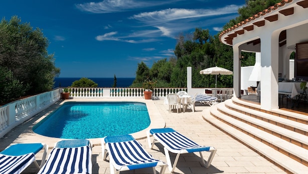 A pool area with lounge chairs, a pergola, and a view of the sea. - Villa MAESO, sea views, air conditioning, pool, 8 pax (Son Bou)