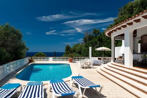 A pool area with lounge chairs, a pergola, and a view of the sea. - Villa MAESO, sea views, air conditioning, pool, 8 pax (Son Bou)