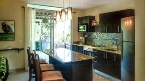 Une cuisine moderne avec des meubles de couleur sombre, un îlot central et un coin repas avec des chaises.