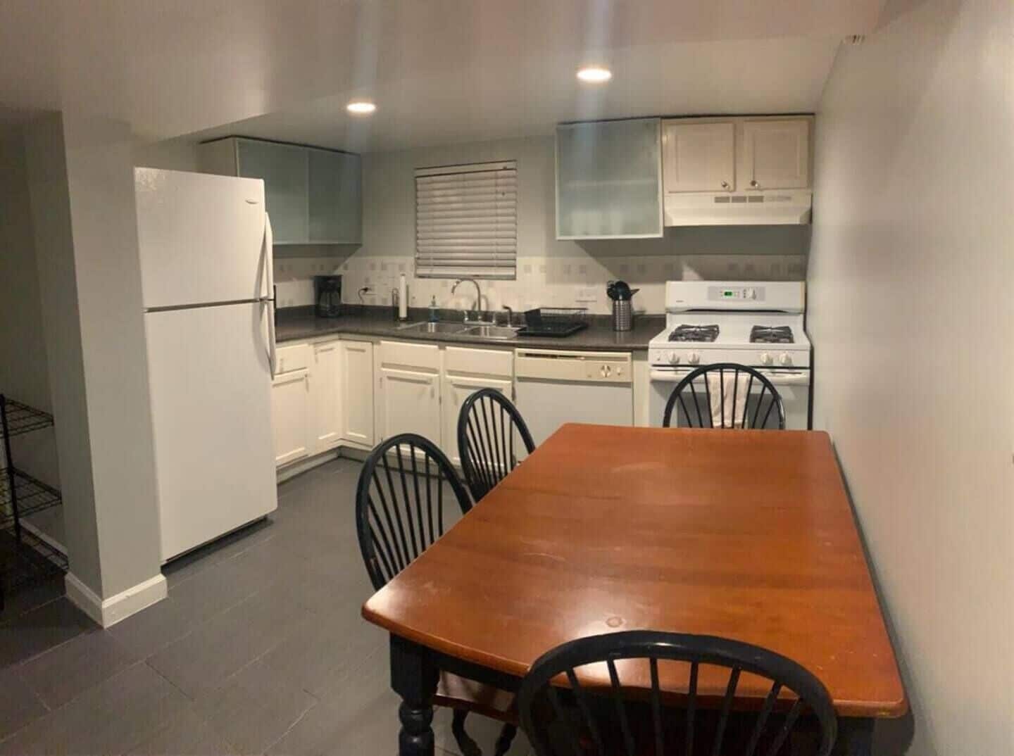 A compact kitchen with white cabinets, a stove, and a dining table with chairs.
