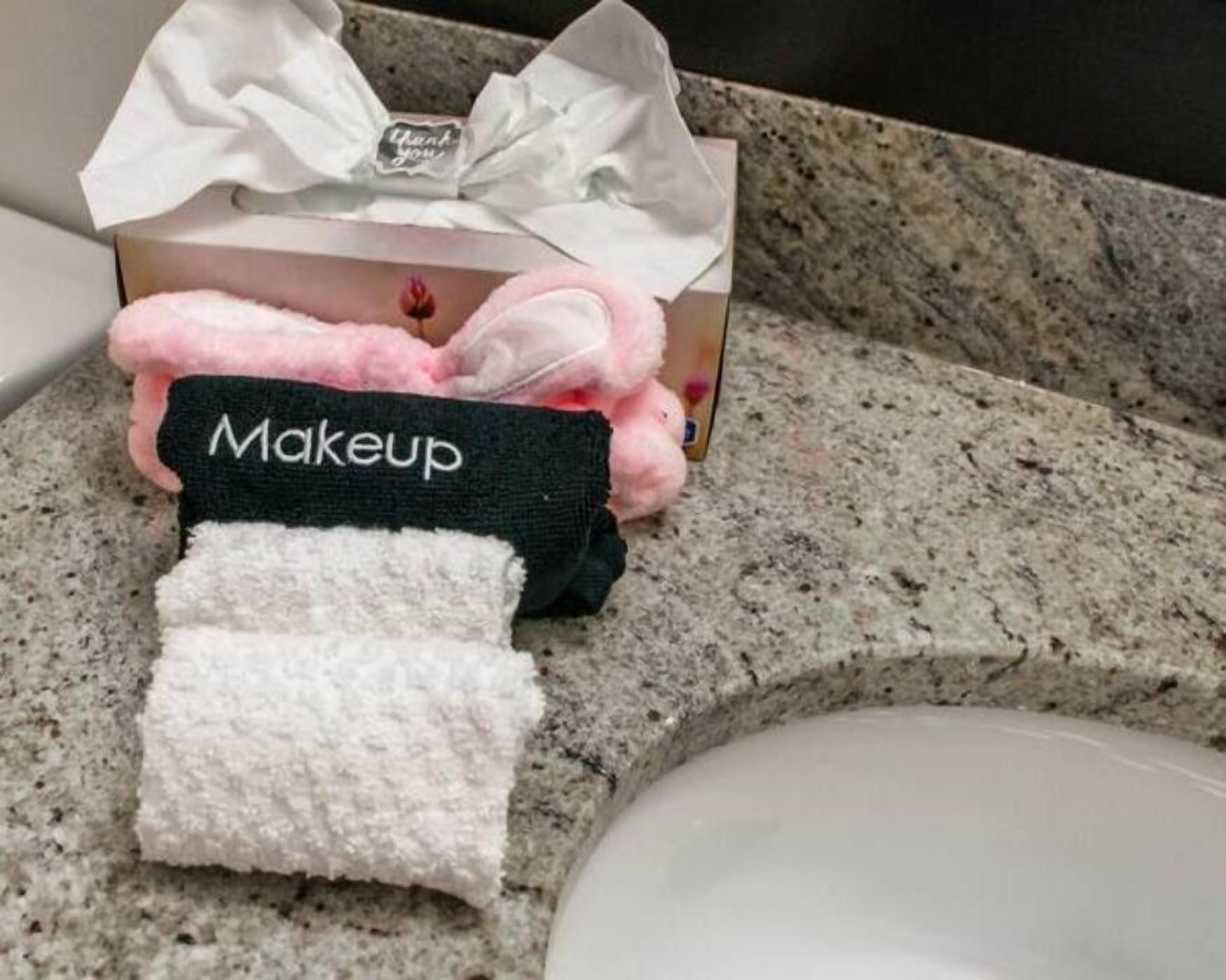 Une salle de bain dotée d’un comptoir en granit, d’un lavabo blanc et d’une serviette moelleuse aux couleurs rose et blanc, sur laquelle est inscrit le mot « Maquillage ».