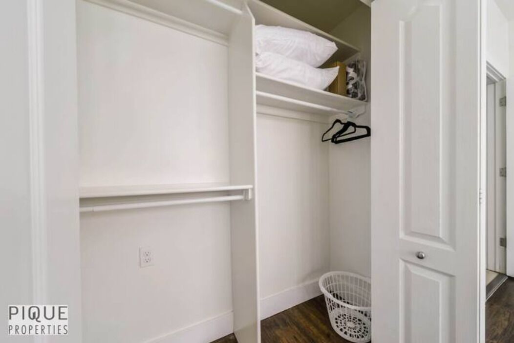 Un placard blanc avec des étagères, une tringle et un panier à linge.
