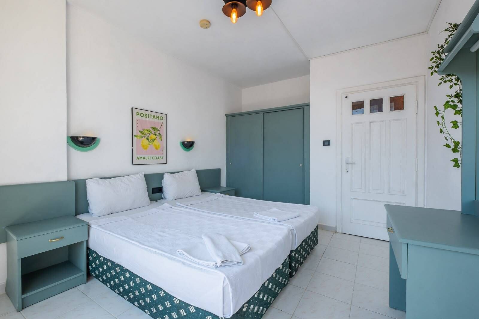 A bedroom with a bed, nightstands, a wardrobe, and a door.