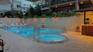 A pool area with two pools, lounge chairs, and a wooden deck. - Casa Cleo Suite (Alanya)