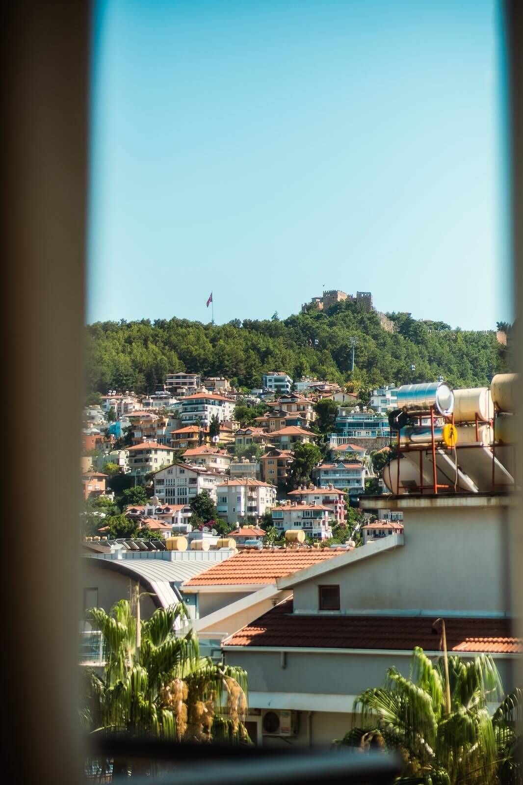 A residential area with a hilltop castle, a flag, and a view of a water tower.