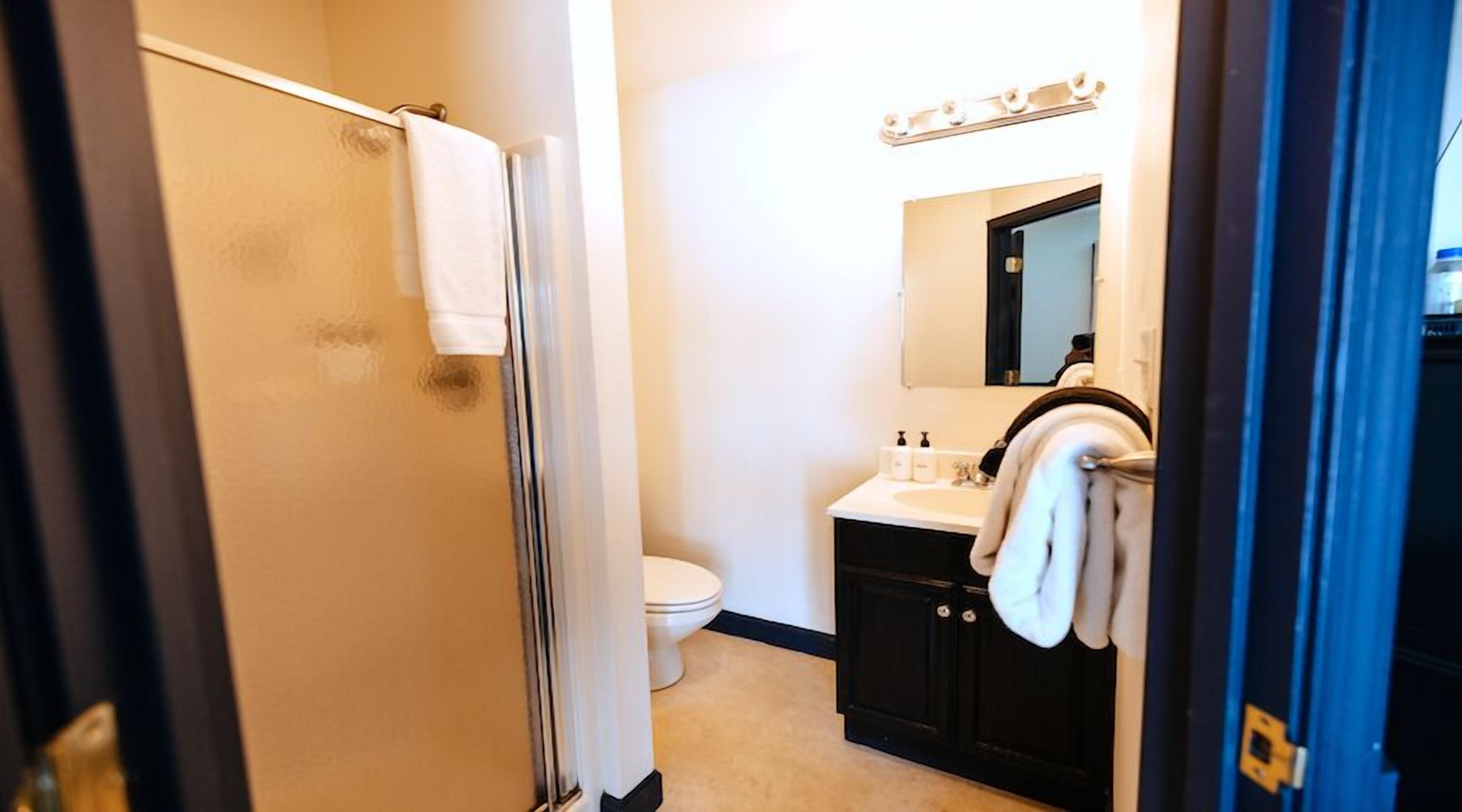 A bathroom with a shower, toilet, sink, and mirror.