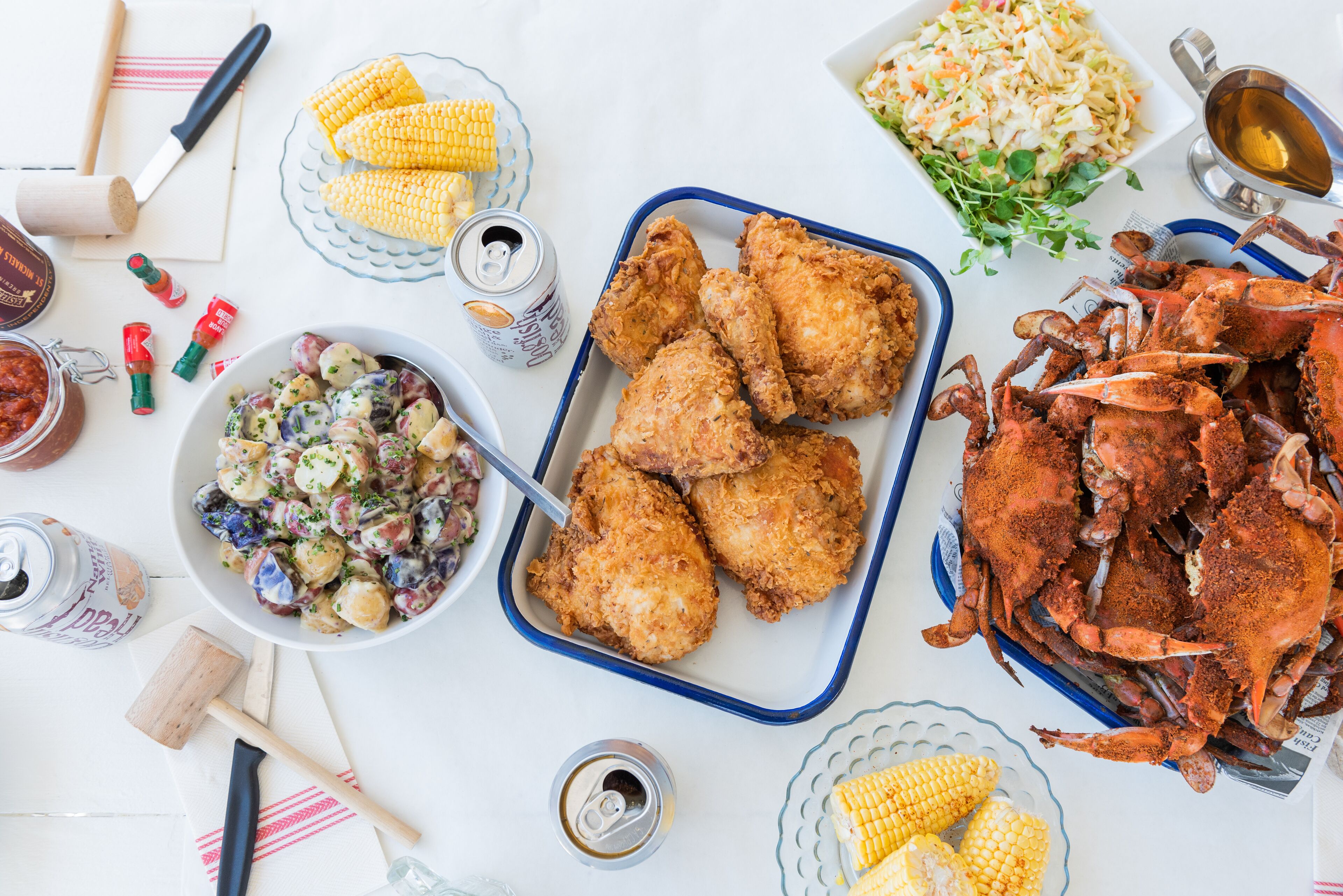 Une table garnie de différents plats, notamment du poulet frit, du crabe et de la salade de chou.