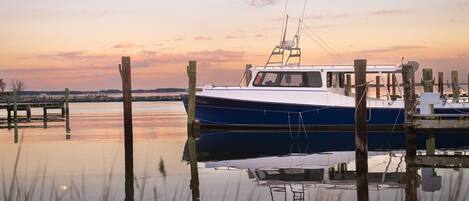 A boat docked at a pier with a calm water surface reflecting the sky and surrounding structures.