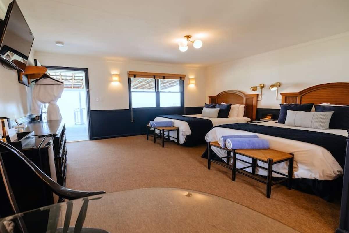 Une chambre d’hôtel avec deux lits, un bureau, une chaise et un téléviseur.
