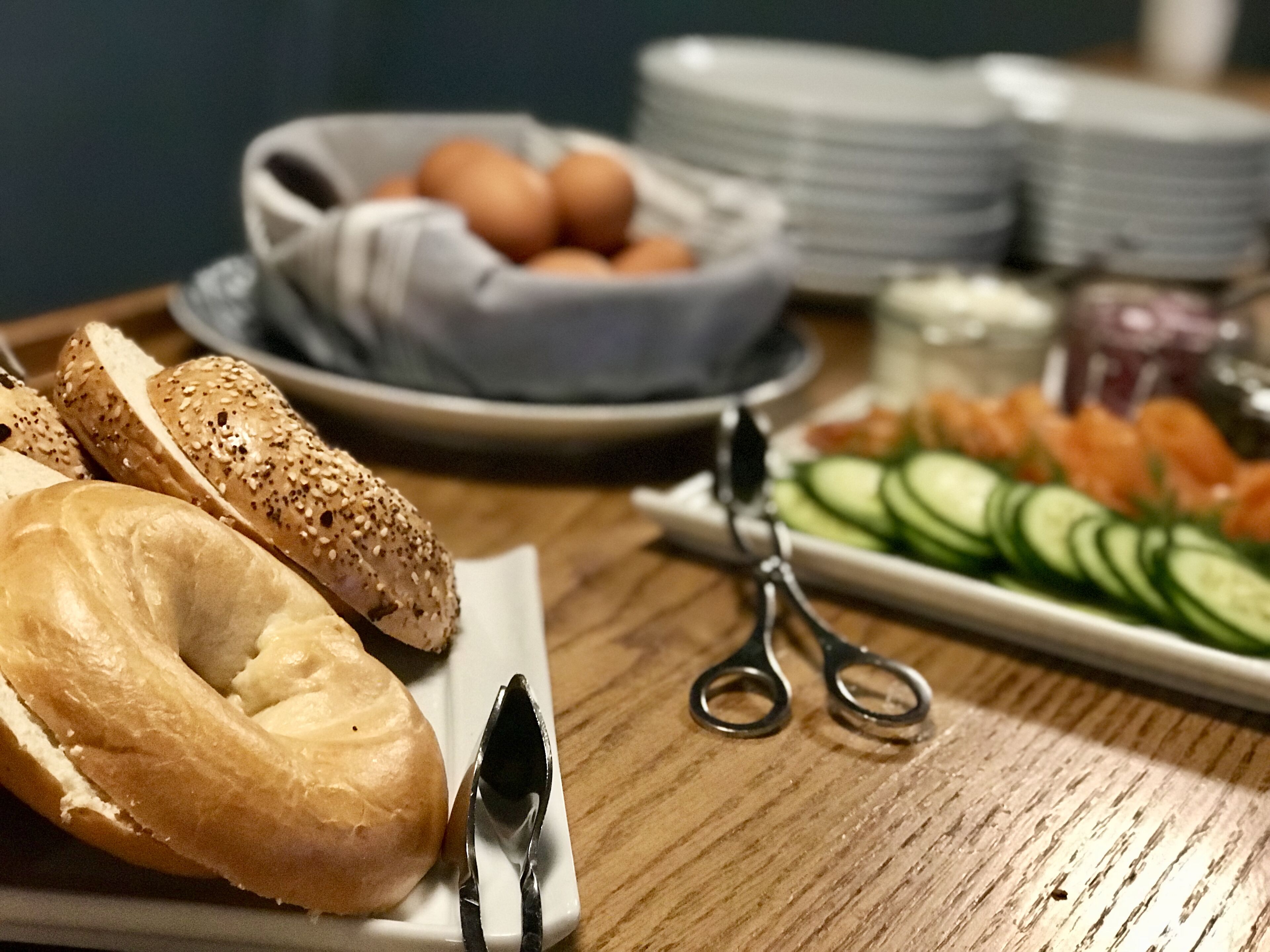 Ein Frühstückstisch mit Bagels, Eiern und Gurkenscheiben.