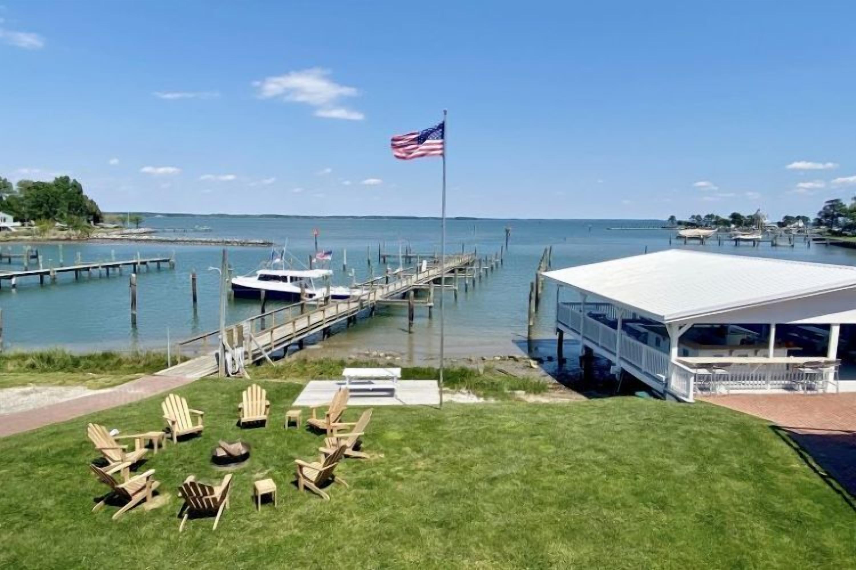 A waterfront property with a dock, a covered seating area, and a flag.