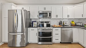 A modern kitchen with white cabinets, stainless steel appliances, and a black countertop. - Welcome Home! 10 mins to the Horse Park, Bourbon Trail & We're Pet Friendly (Georgetown)