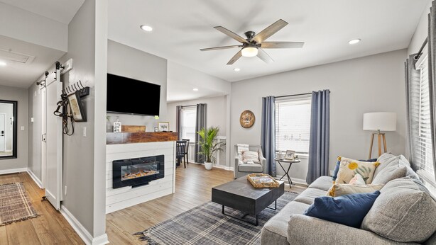 A modern living room with a fireplace, a ceiling fan, a sofa, and a coffee table. - Welcome Home! 10 mins to the Horse Park, Bourbon Trail & We're Pet Friendly (Georgetown)