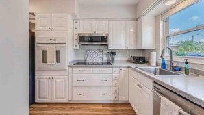 Una cocina con armarios blancos, un microondas, un fregadero y una ventana con vistas.