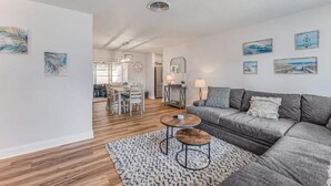 Una sala de estar moderna con un sofá gris, una mesa de centro y un comedor con una mesa y sillas.