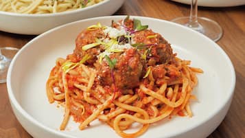 Una mesa con tres platos: espagueti con albóndigas, ensalada de pasta y ensalada de verduras.