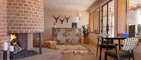 A cozy living room with a brick fireplace, a round table, and a comfortable chair.