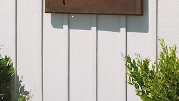 Une enseigne en métal au style rustique, portant les mots « cicco papi », fixée à un mur en bois peint en blanc.