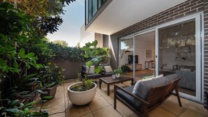 En terrasse med sofa, sofabord og krukker med planter.