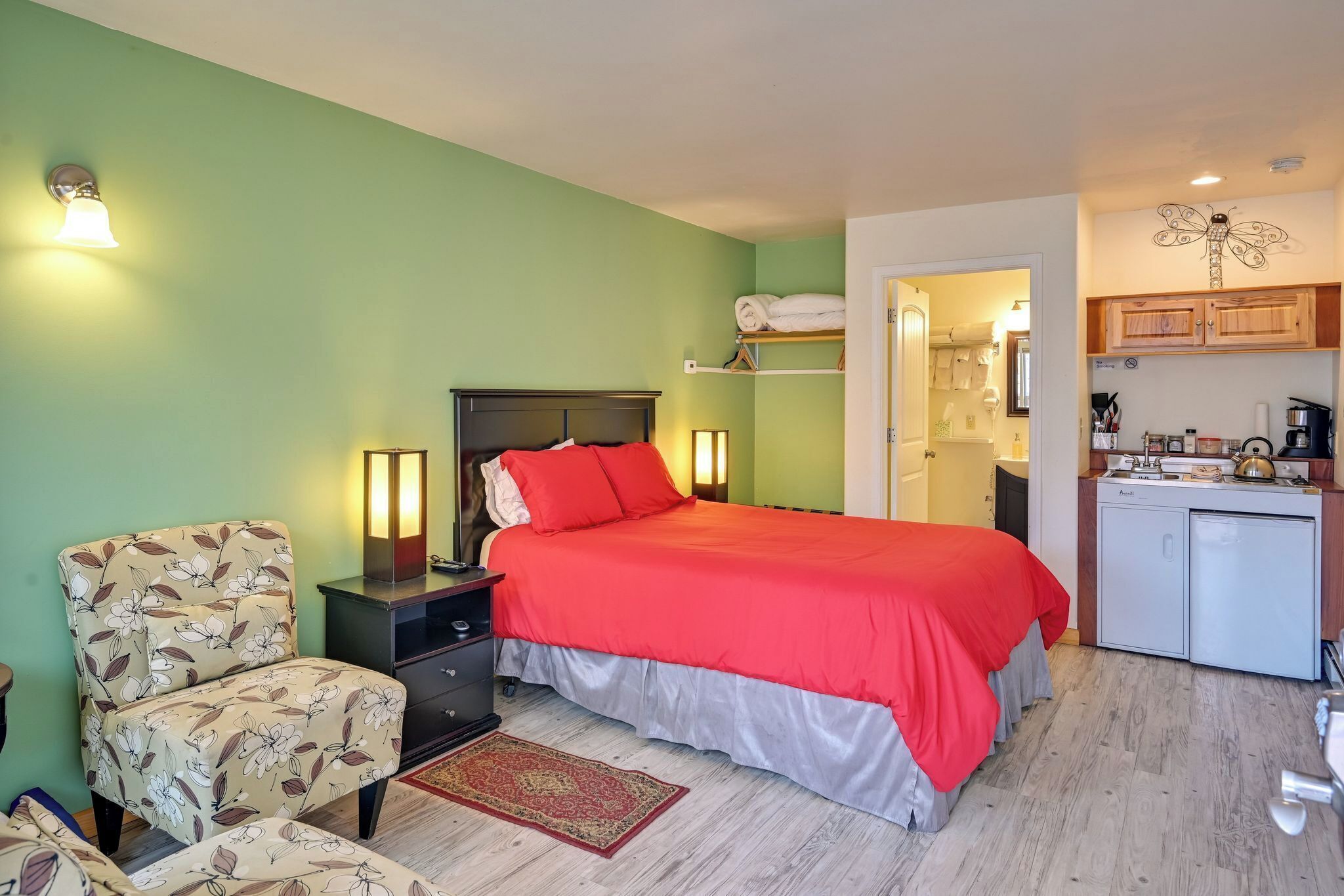 Une chambre à coucher comprenant un lit, des tables de chevet, une chaise, un bureau et un coin cuisine.