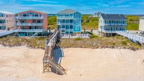 A beachfront property with multiple multi-story buildings, a wooden boardwalk leading to the beach, and a clear sky. - Spacious Oceanfront | Sleeps 30!
 (North Topsail Beach)
