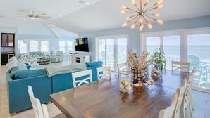 A spacious living area with a large dining table, blue sofa, and a view of the ocean. - Spacious Oceanfront | Sleeps 30!
 (North Topsail Beach)