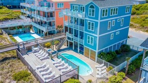 A multi-story hotel with a pool, balconies, and a deck area with lounge chairs. - Spacious Oceanfront | Sleeps 30!
 (North Topsail Beach)