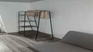 Une pièce avec un canapé gris, une étagère en métal et un sol à rayures.