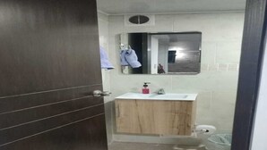 Une salle de bain avec un meuble-lavabo en bois, un miroir, un lavabo et des toilettes.