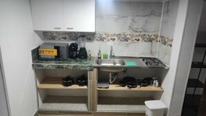 Une cuisine compacte équipée d’un évier, d’un four à micro-ondes et d’un petit plan de travail.