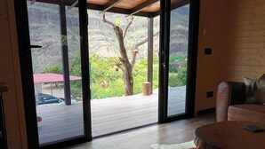 A room with a sliding glass door leading to an outdoor patio, a wooden table, and a leather sofa. -  Cabin with jacuzzi in its 800 meter private land with fruit trees.  (fataga)