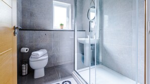 A modern bathroom with a glass shower enclosure, a toilet, and a sink.