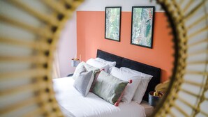 A bed with multiple pillows and a headboard, framed by a mirror with a decorative frame.
