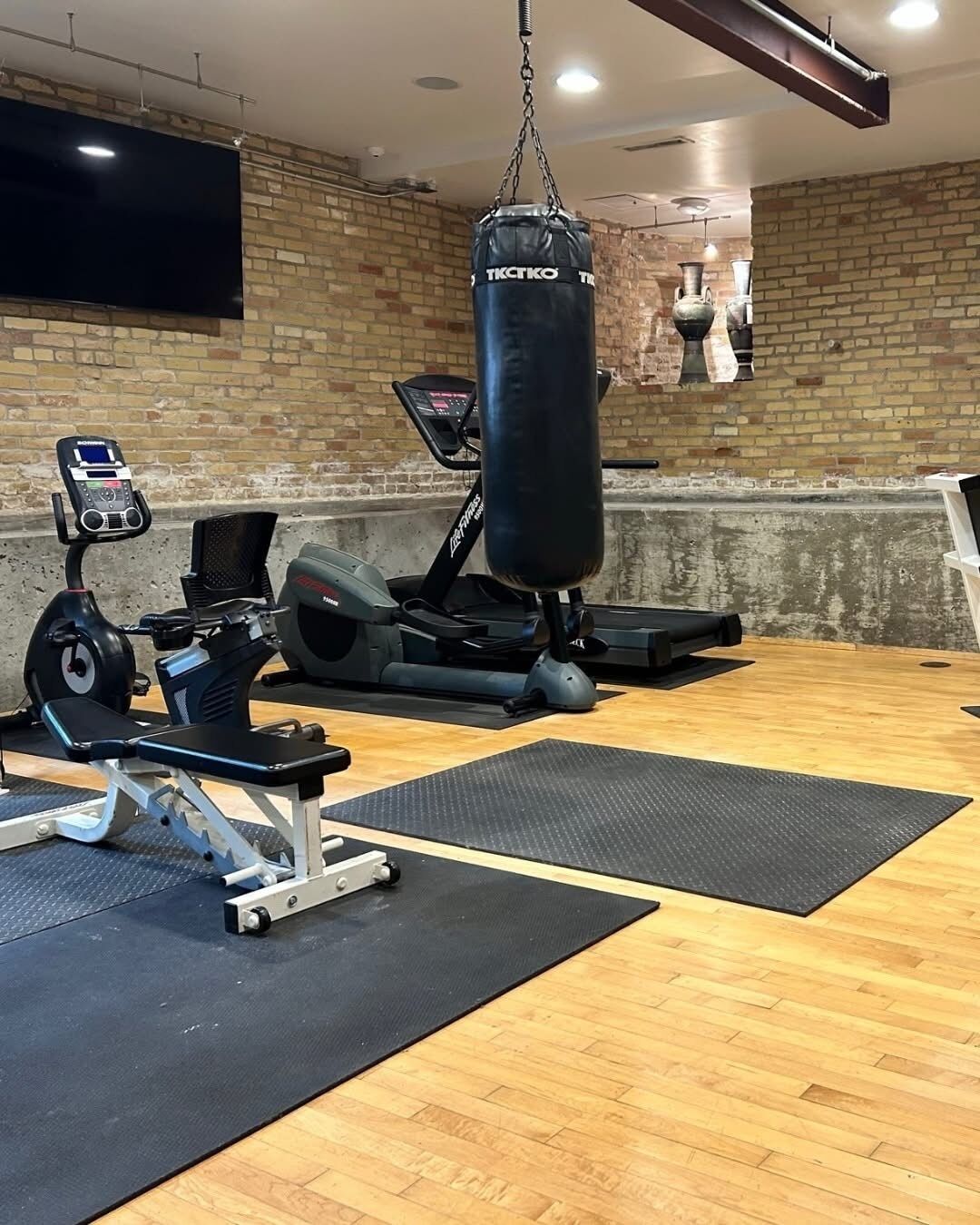 A gym with exercise equipment, including a punching bag, stationary bike, and weight bench.