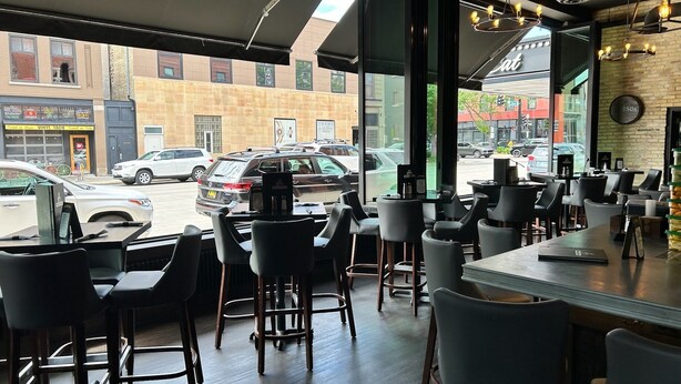 A restaurant interior with modern furniture, large windows, and a view of the street outside. - Hotel Donaldson (Fargo)