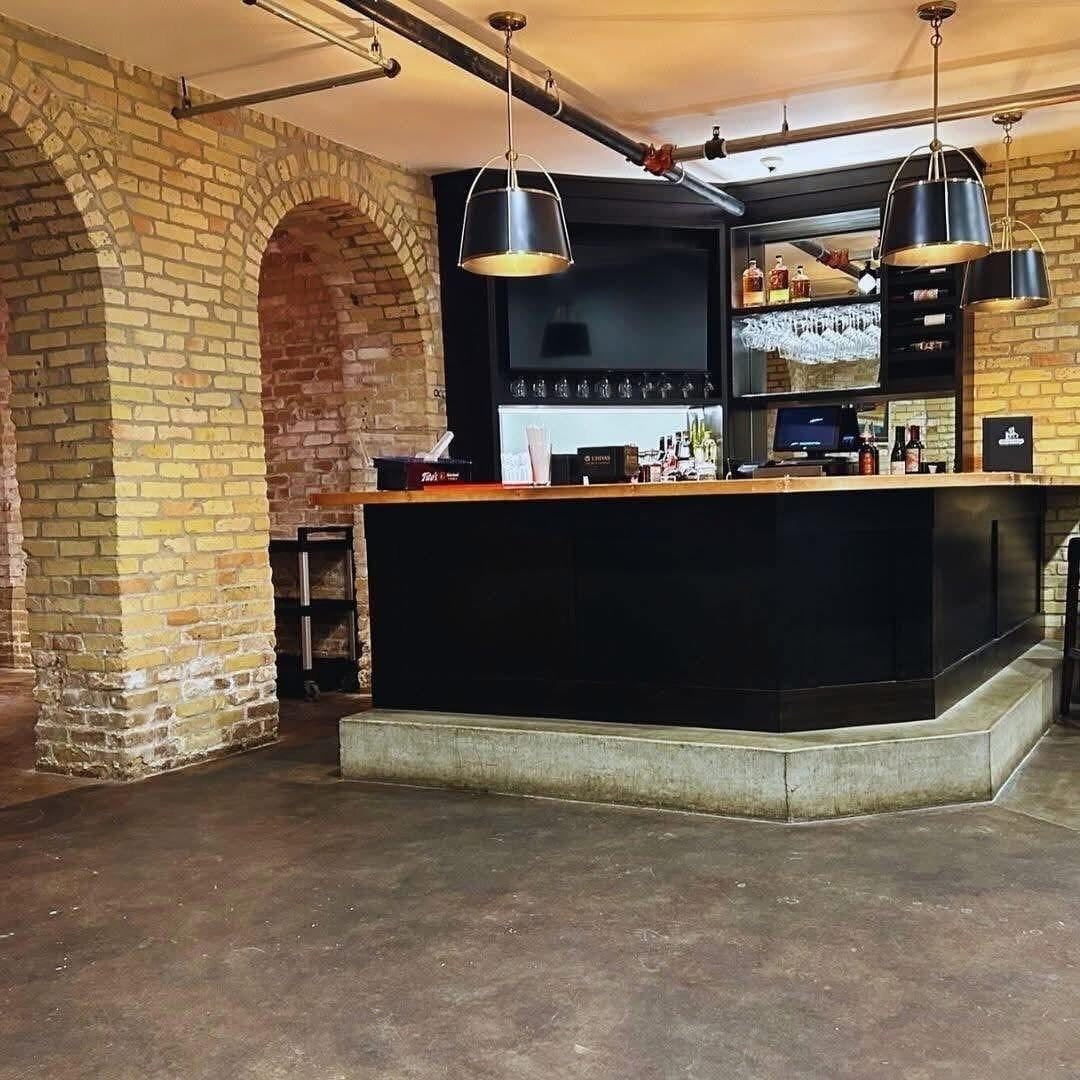 A bar area with a brick wall, a black counter, and hanging lights.